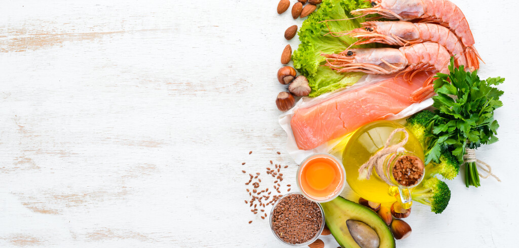 Balanced Keto diet. Healthy food: avocado, fish, shrimp, broccoli, flax, nuts, egg, parsley. Top view. Free space for your text.