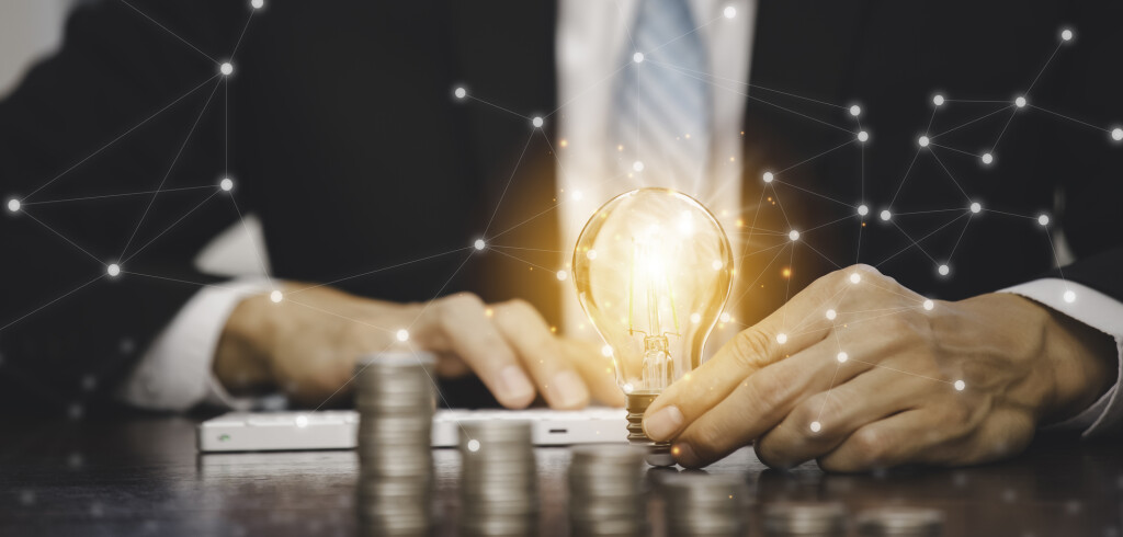 Businessman hand holding light bulb with line connect and Coins stack on the wooden table , Saving ideas and investment budget, Creative ideas concept of saving money concept, Copy space