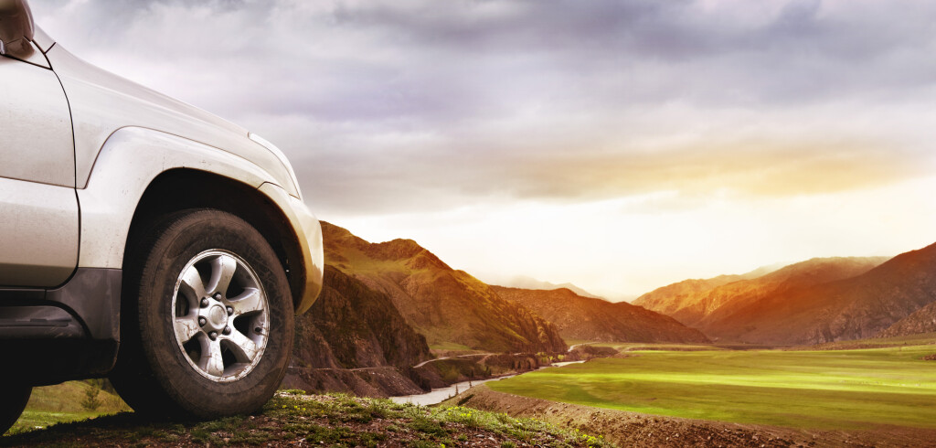 Offroad car concept. Big car wheel on background of mountains and sunset