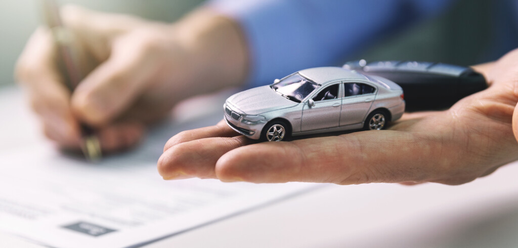 buy new car concept - scale model and key in dealer hand