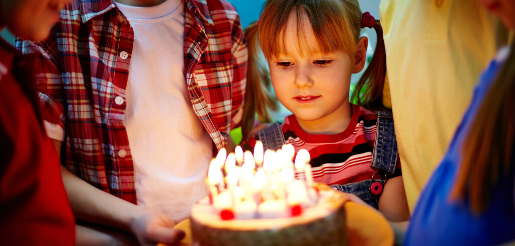 Group of adorable kids looking at birthday cake with candles