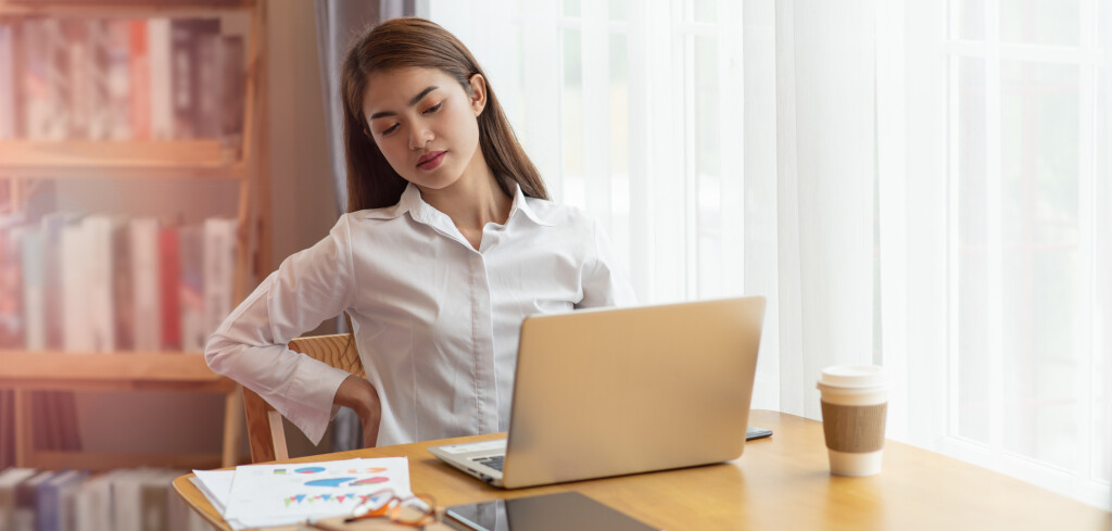 Portrait of businesswoman feeling pain in spine back after sedentary computer work sitting in bad posture in office