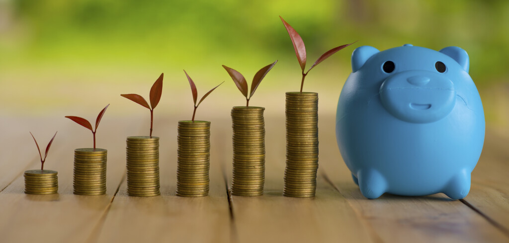 A piggy bank put on the stacking gold coins and blackboard house