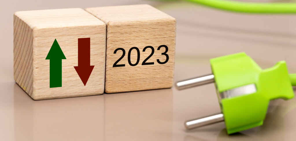 energy prices in 2023, energy crisis concept, rising cost of sourcing raw materials, wooden blocks with date, green and red arrow up and down, green cable with plug