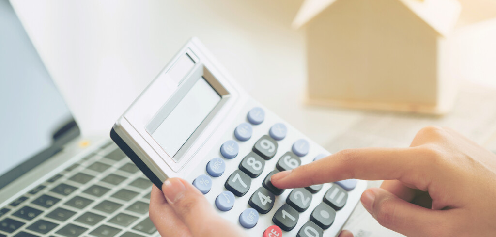 Woman accountant or bank worker uses calculator in the office to calculate house loan credit bureaucracy.