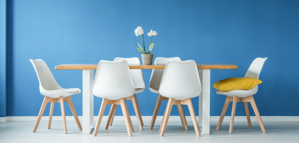 Blue dining room interior with a big table, white chairs and yellow chandelier